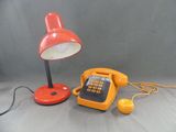 un téléphone jaune et une lampe rouge posés sur une table