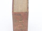 a small vase with a book on it on a white surface