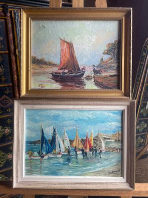 two paintings of sailboats on display in front of a painting easel