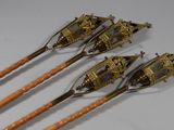 three antique brass spoons with wooden handles on a white surface
