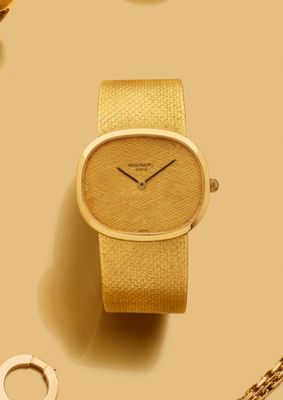 une montre en or posée sur une table, à côté d'autres objets