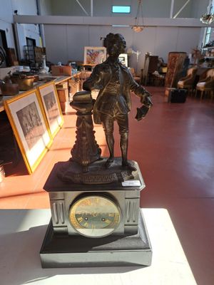 une statue représentant un homme tenant une horloge dans une pièce