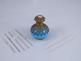 a small blue vase with needles on a white table