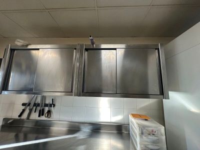 une cuisine avec des placards en inox et des couteaux posés sur le plan de travail