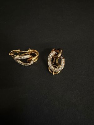deux boucles d'oreilles en or et diamants posées sur une surface noire