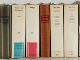 several books are lined up on a shelf in front of a white wall