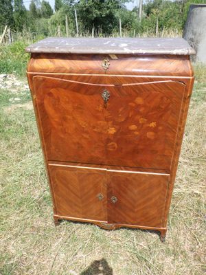 une vieille commode en bois posée dans un champ d'herbe