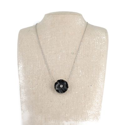 Le collier est posé sur un mannequin orné d'une fleur noire.