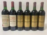 six bottles of wine are lined up in a row on a white surface