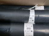 plusieurs rouleaux de plastique noir posés dans une boîte, elle-même posée sur un carton