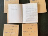 four open notebooks sitting on top of a table with writing on them