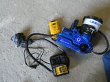 une photo d'une perceuse électrique bleue et jaune et d'autres outils posés par terre