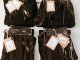 four pairs of brown velvet pants with tags on them sitting on a table