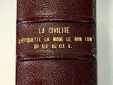 un livre en cuir marron, orné d'une inscription dorée, posé sur une surface blanche