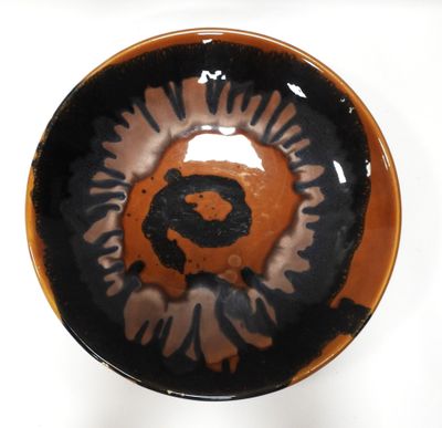 a black and orange bowl with a picture of a bear on it