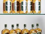 several bottles of liquor are lined up on a glass shelf