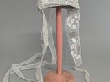 a white hat on a pink stand with a white ribbon