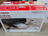 a canon printer sitting on top of a box on the floor