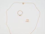 a gold necklace, ring, and earring on a white surface