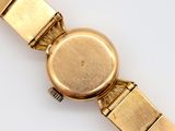 a close up of a gold wrist watch on a white surface