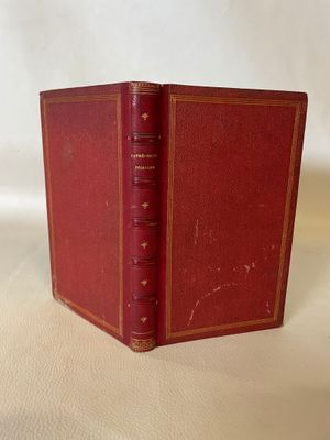 an old red book sitting on top of a white table