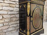 a black and gold cabinet sitting against a stone wall