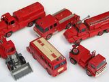 Plusieurs camions de pompiers miniatures sont alignés sur une surface blanche