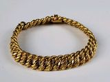 gros plan d'un bracelet en or sur une surface blanche