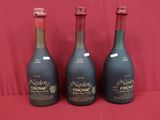 trois bouteilles de vin sont alignées sur une surface rouge