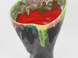 a black vase with a red substance inside of it