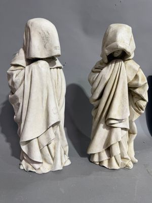three statues of people in hooded clothing standing next to each other