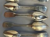 six silver spoons are lined up in a row on a table