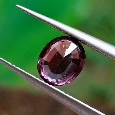 un gros plan sur un diamant violet tenu par une pince