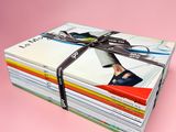 une pile de magazines entourée d'un ruban sur fond rose