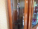 a wooden cabinet with a glass door in the corner of the room