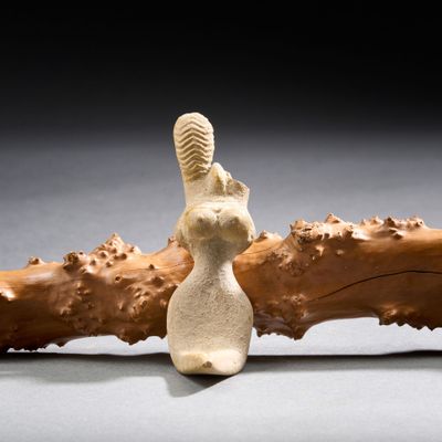 une sculpture représentant un lapin assis sur un morceau de bois