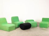 three green chairs and a black ottoman in a white room