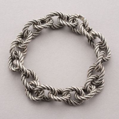 un gros plan d'un bracelet en corde posé sur une surface blanche