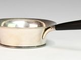 a silver saucepan with a black handle on a white surface