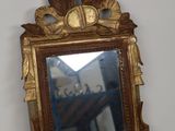 un miroir avec un cadre doré sur un mur blanc