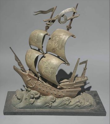 statue of a ship on a wave with a flag on it