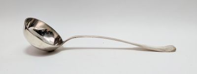 une cuillère en argent avec un manche de cuillère sur une surface blanche