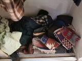 a giraffe standing next to a pile of clothes in a closet