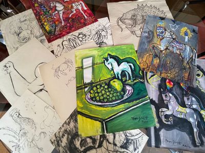 many drawings on a table with a cat on top of it