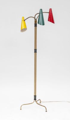 a metal and wood floor lamp with three colored lamps on it
