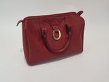 a red handbag with a gold ring on the handle