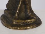 a bronze statue of a woman with a hat and a cane