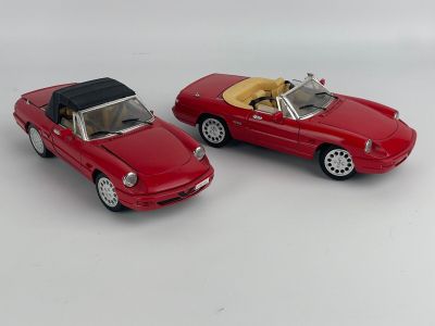 two red toy cars sitting side by side on a white surface