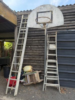 une échelle appuyée contre un panier de basket devant un immeuble