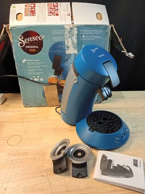 une cafetière bleue posée sur une table à côté d'une boîte de café